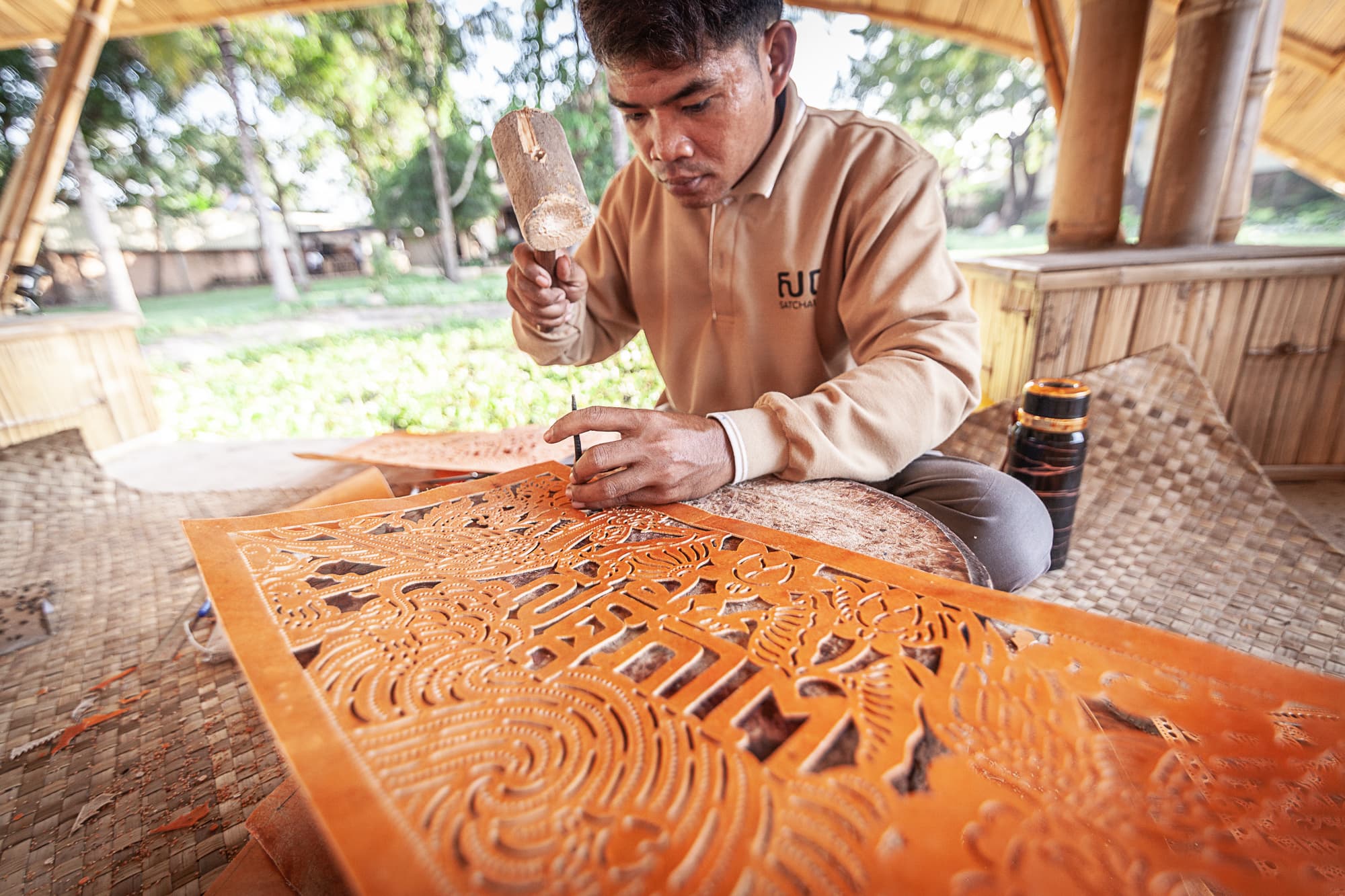 An artisan carving an intricate decorative relief panel.