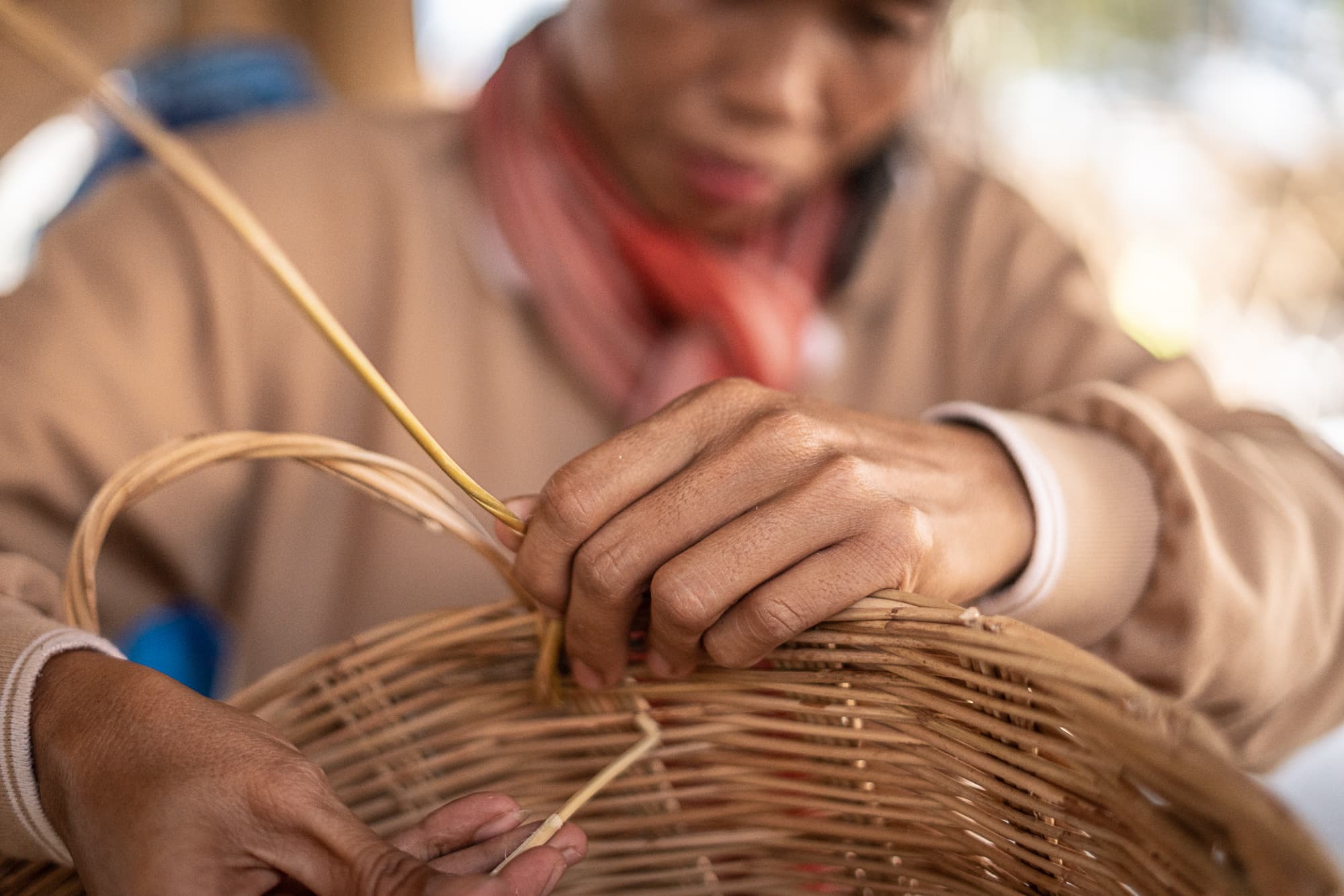An artisan weaving a rattan basket by hand.