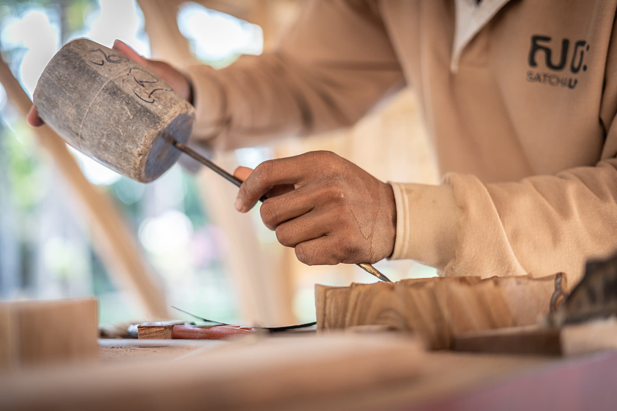 An artisan carving wood with a mallet and chisel.