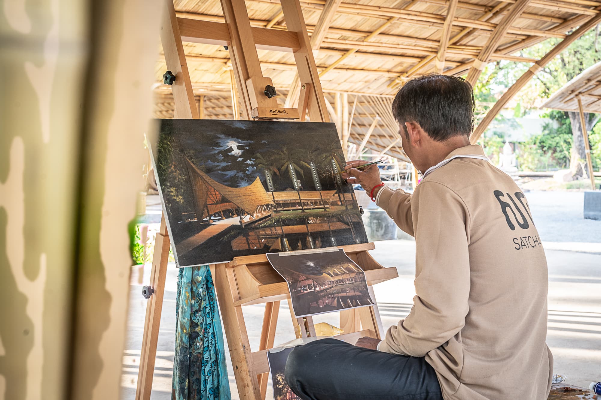 An artisan painting a canvas of the Satcha bamboo center.